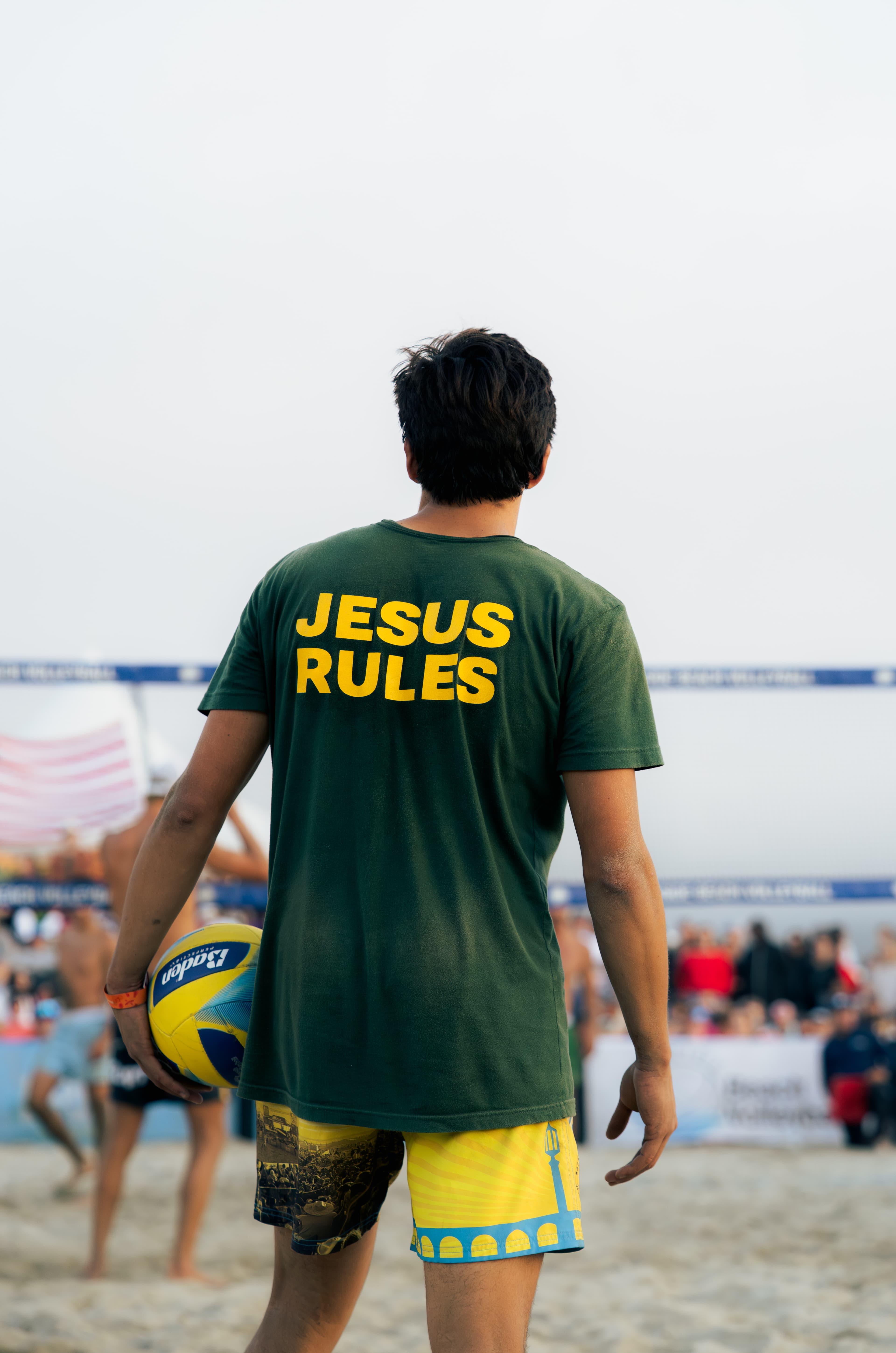 Diego in Jesus Rules tee holding volleyball